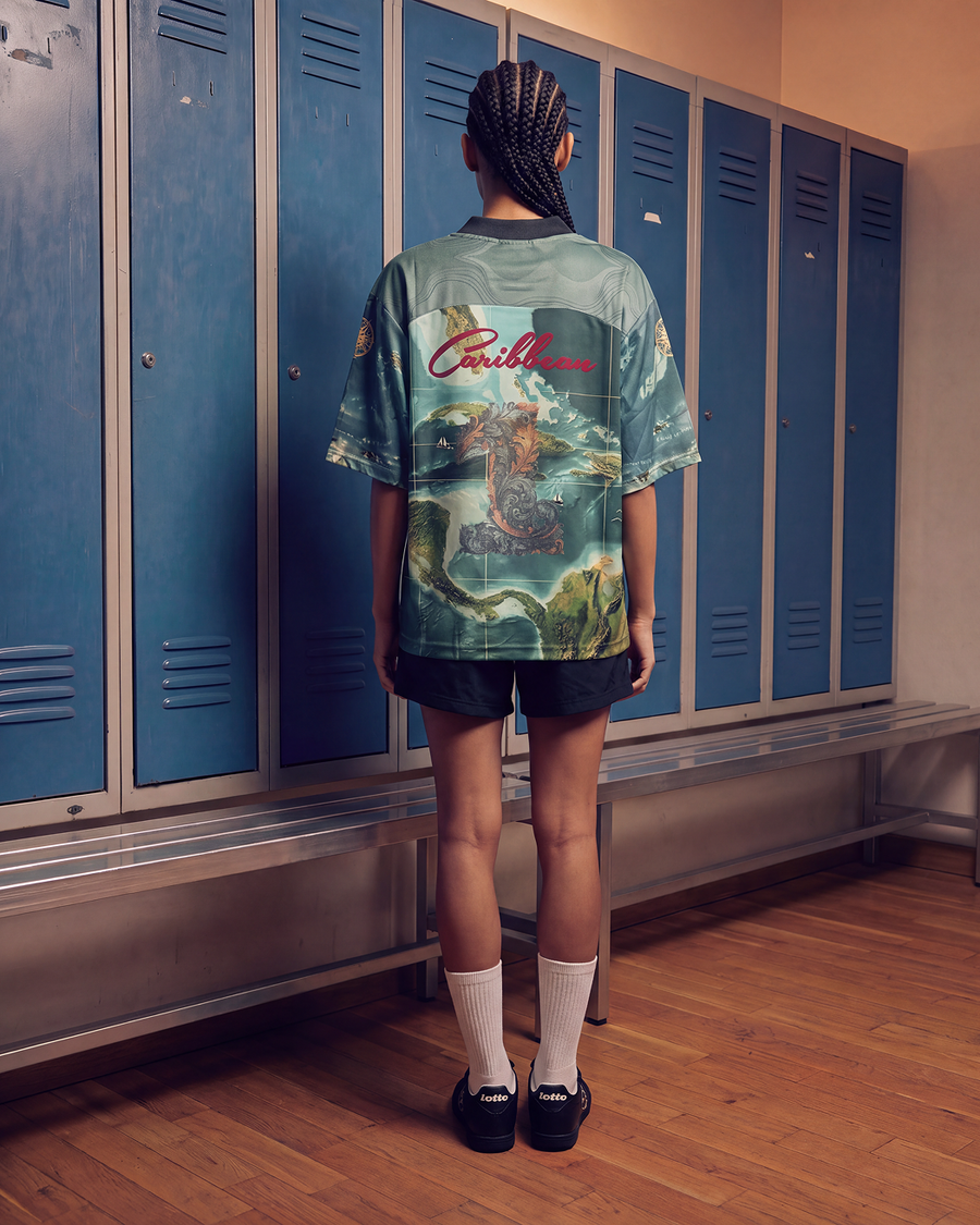 Girl standing in front of a wall of lockers wearing the LOTTO X Joshua Joseph jersey back view